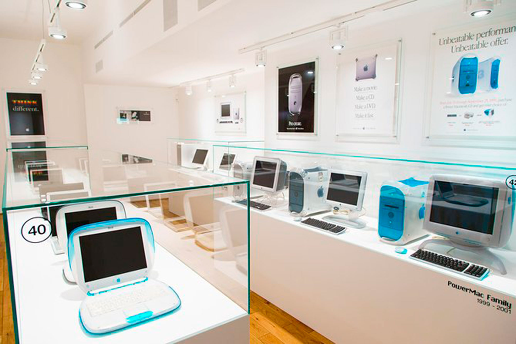 Exposició d'ordinadors Apple clàssics de colors, amb un iBook blau en primer terme i la família Power Mac al fons