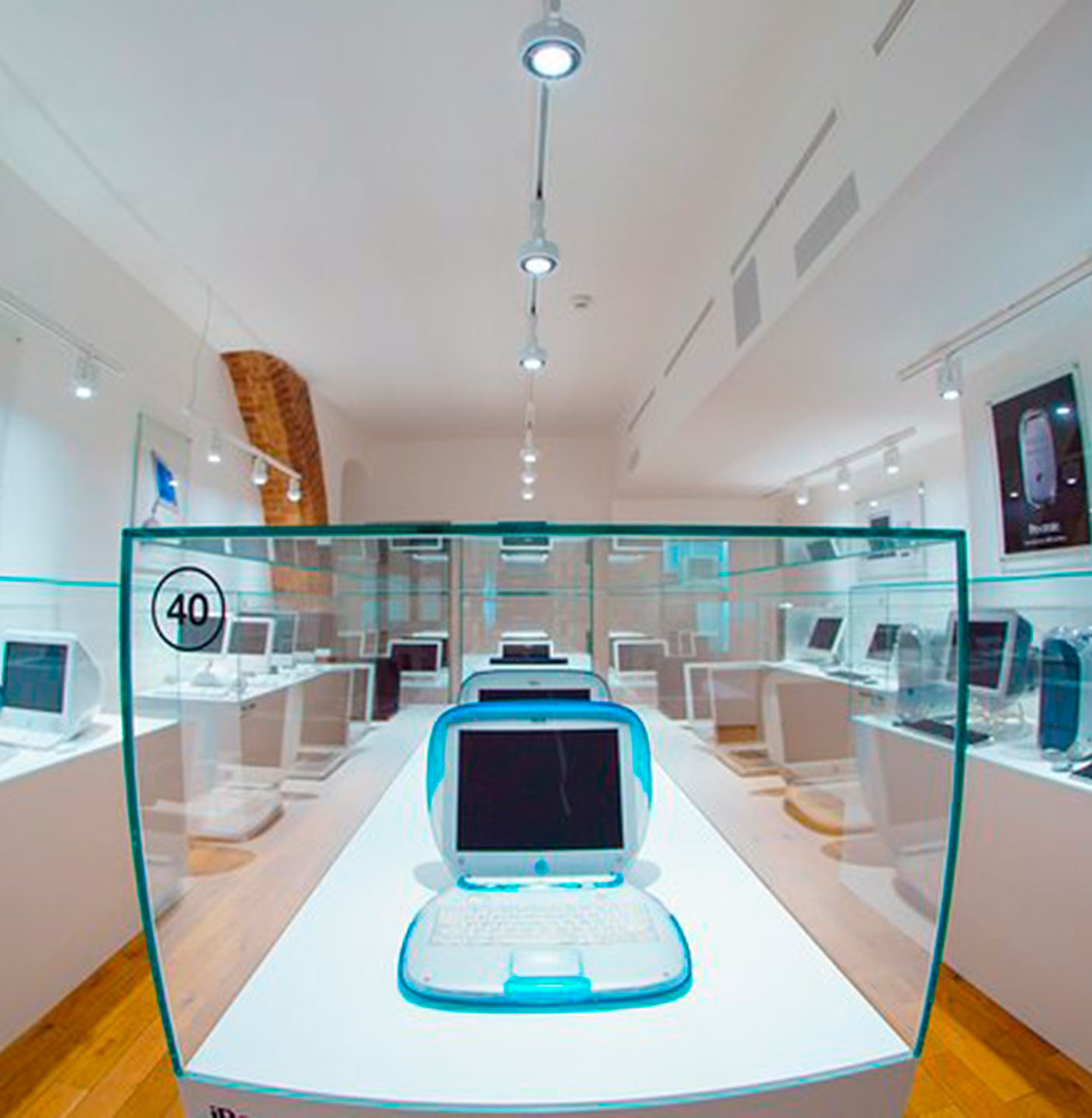 Sala d'exposició amb vitrines d'iMac i Power Mac de colors a banda i banda, i un iBook blau a la vitrina central